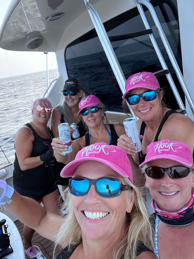 A group of women wearing pink hats and sunglasses on a boat