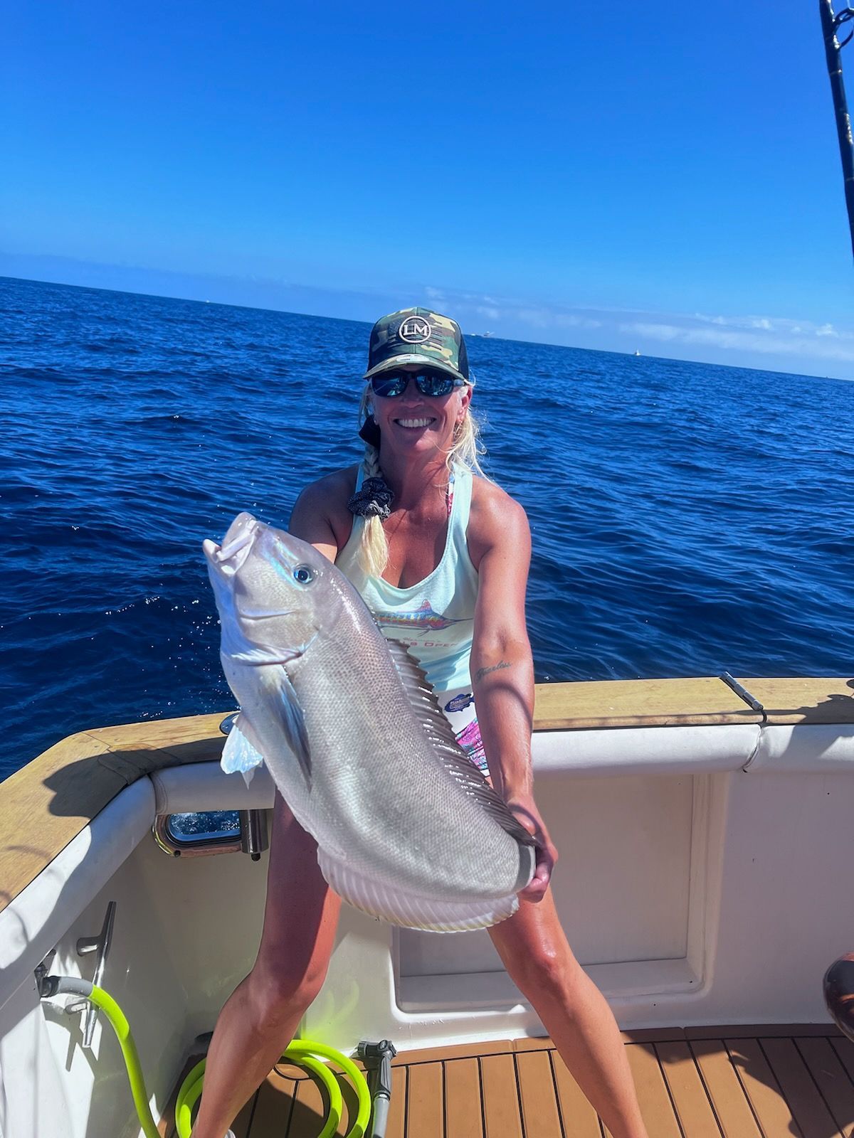 A woman is holding a large fish on a boat