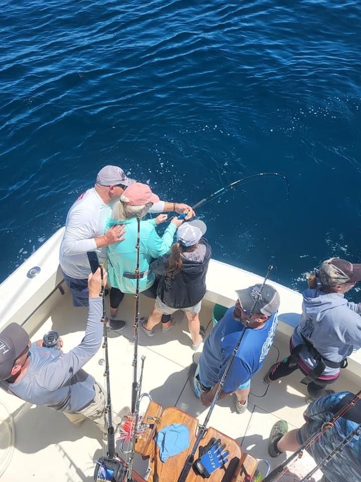 A group of people are fishing on a boat in the ocean