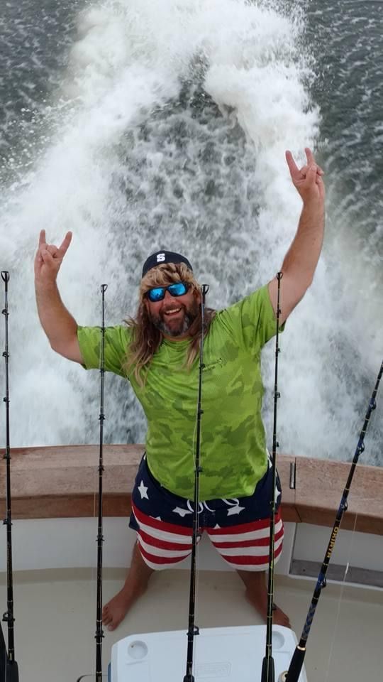A man is sitting on a boat with his arms in the air.
