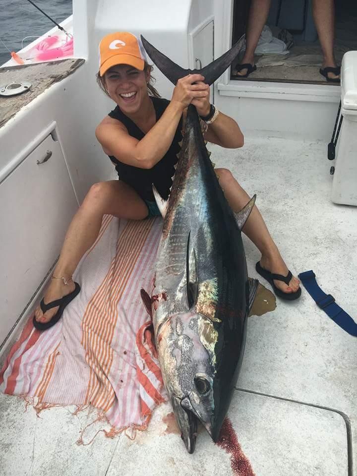 A woman is holding a large fish on a boat