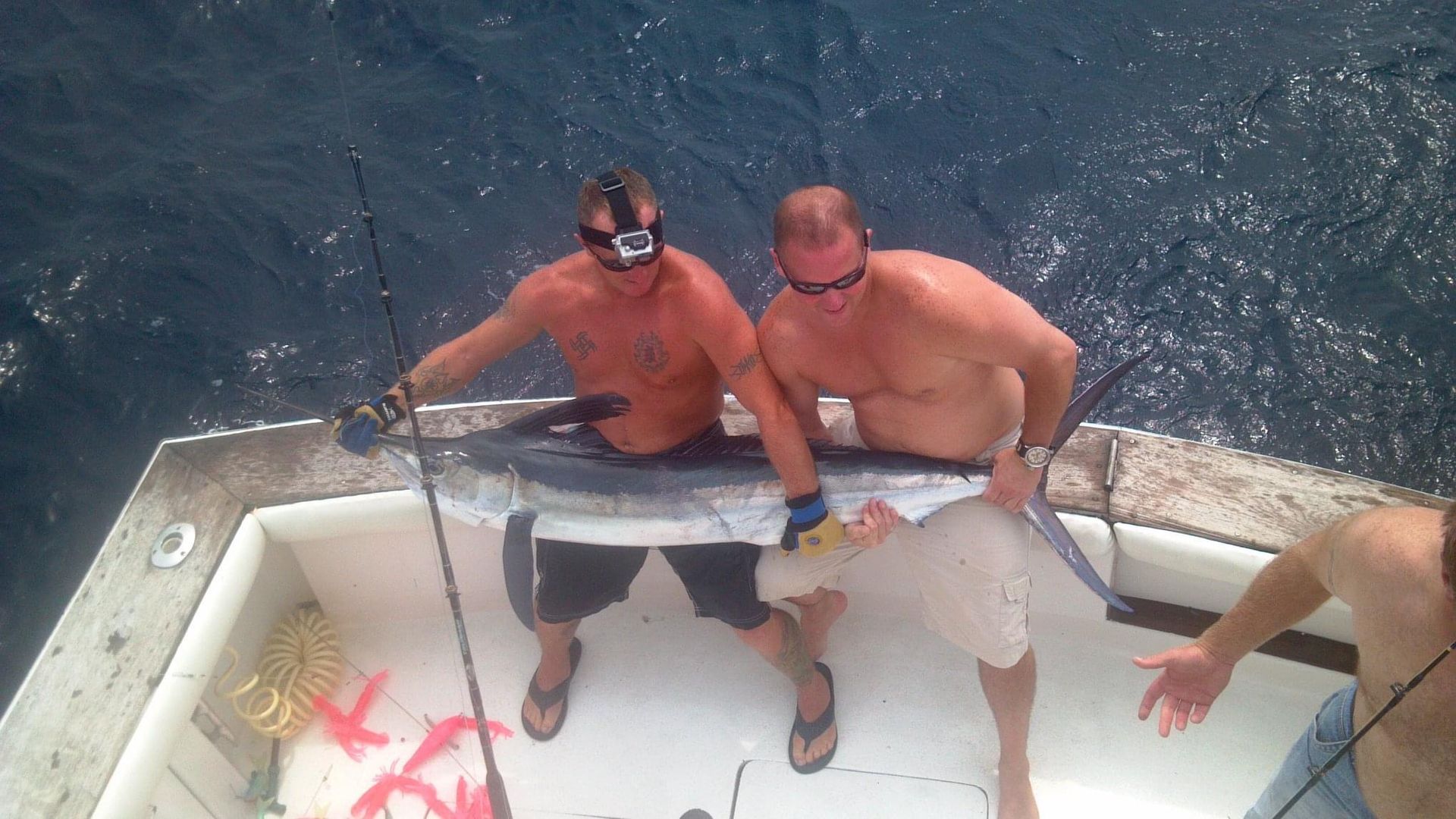 Two men on a boat holding a large fish