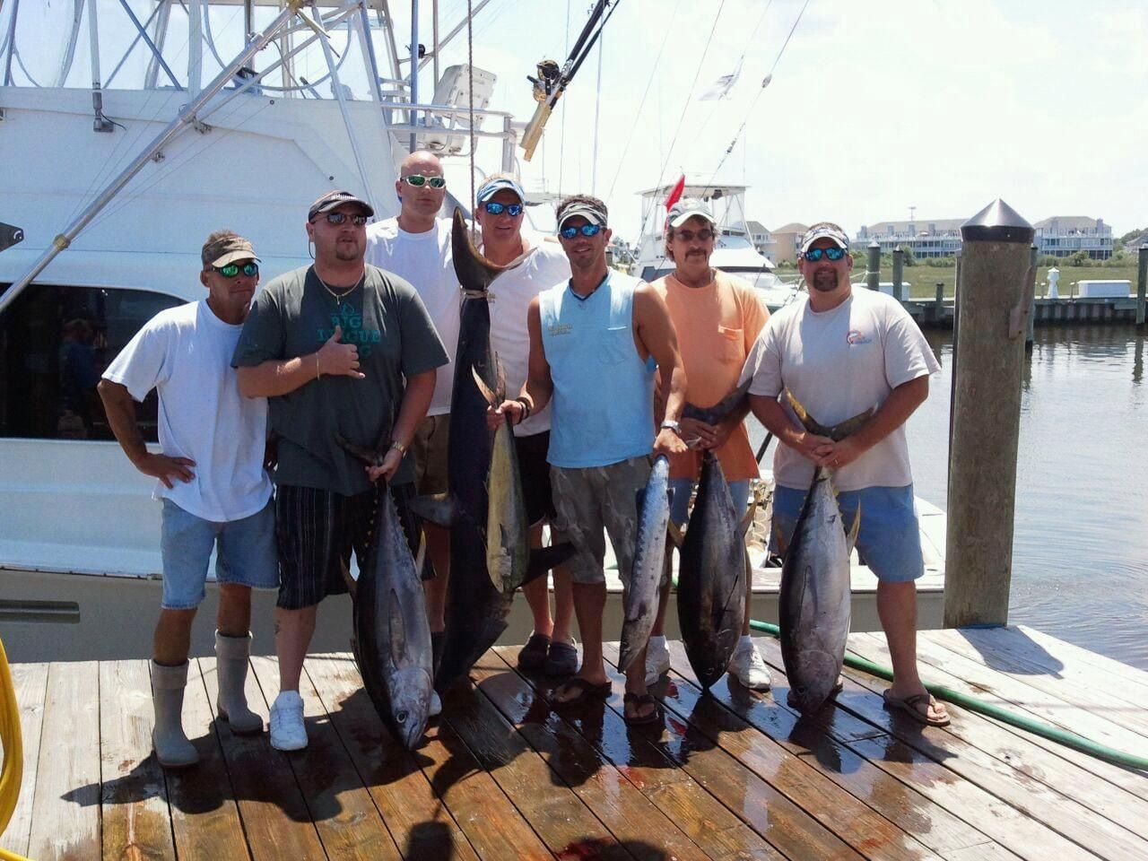 A group of men standing on a dock holding fish