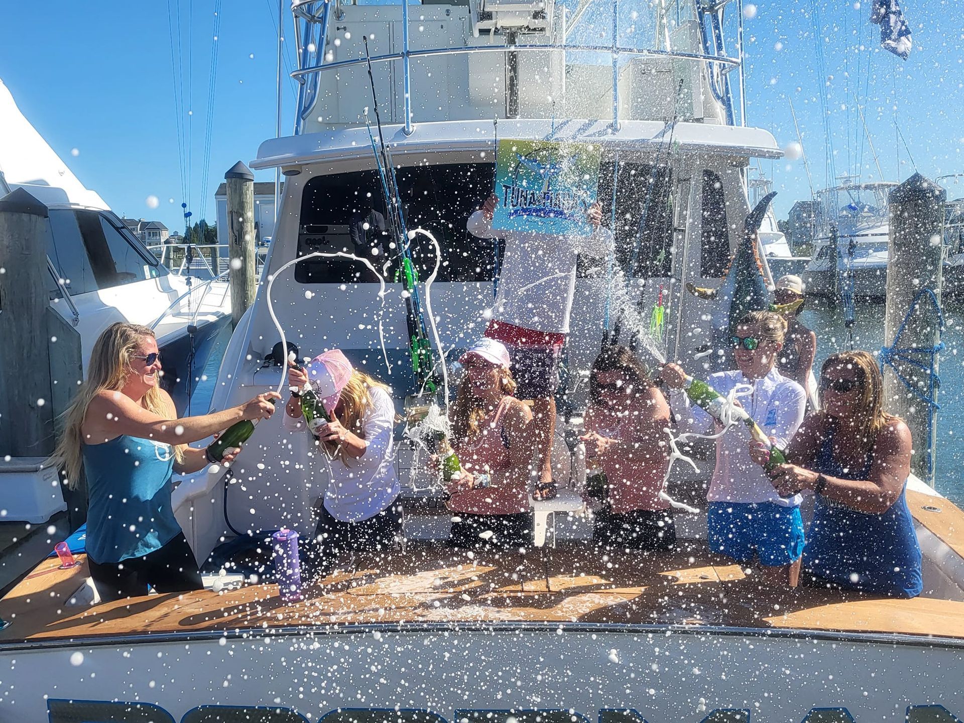 A group of people standing on a boat spraying champagne