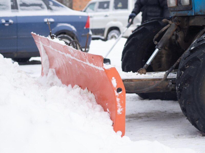 A snow plow is clearing snow from a parking lot.