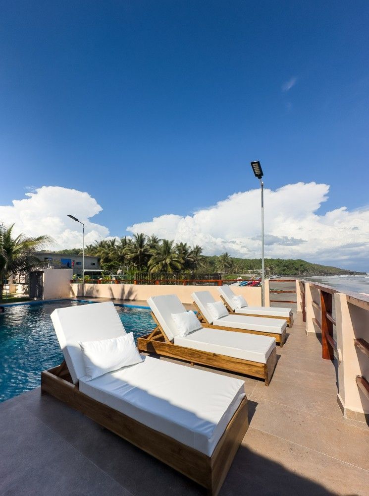 Junto a la piscina con tumbonas frente al mar bajo un cielo azul brillante.