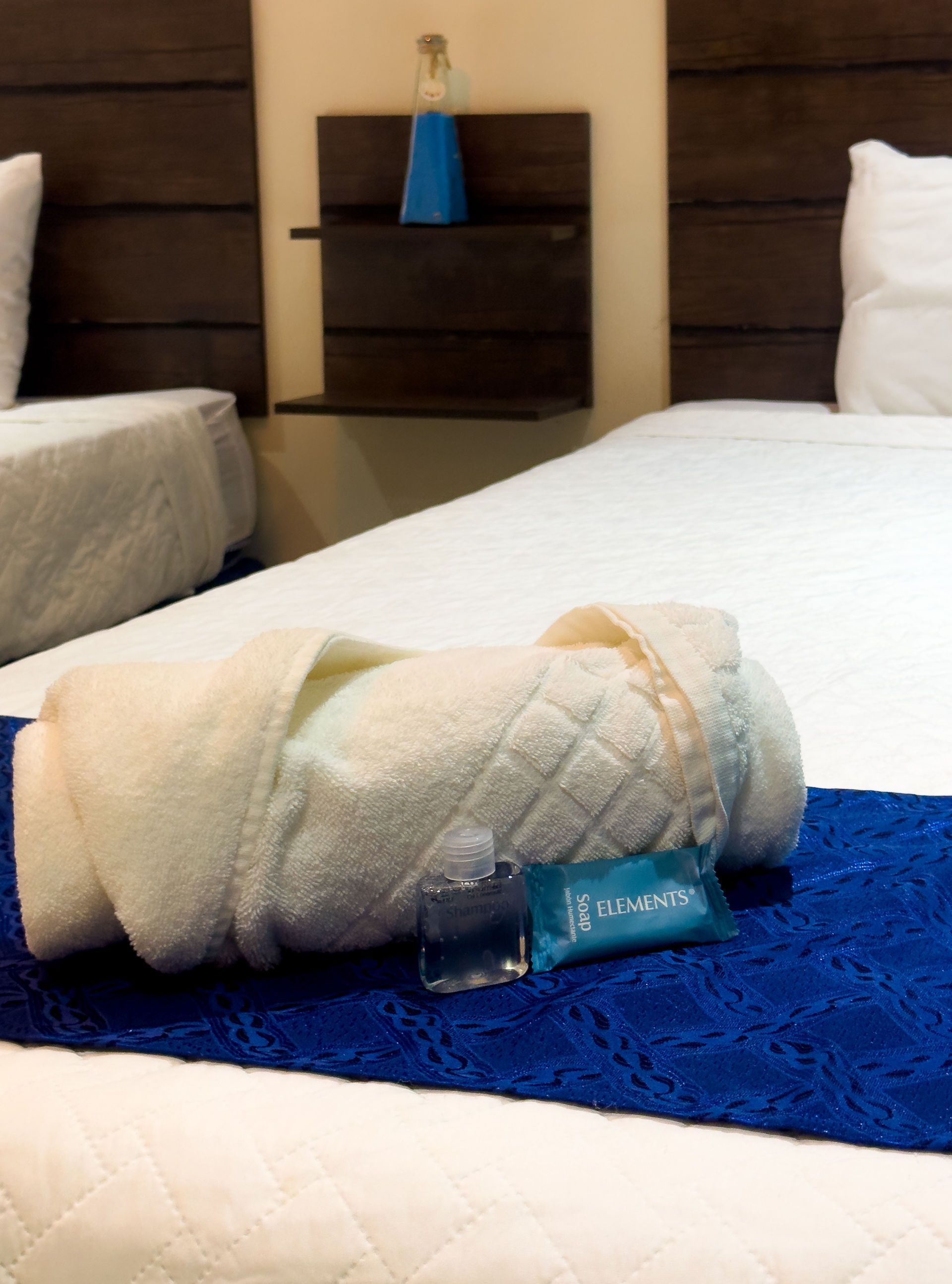 Toalla blanca enrollada con amenidades sobre una cama