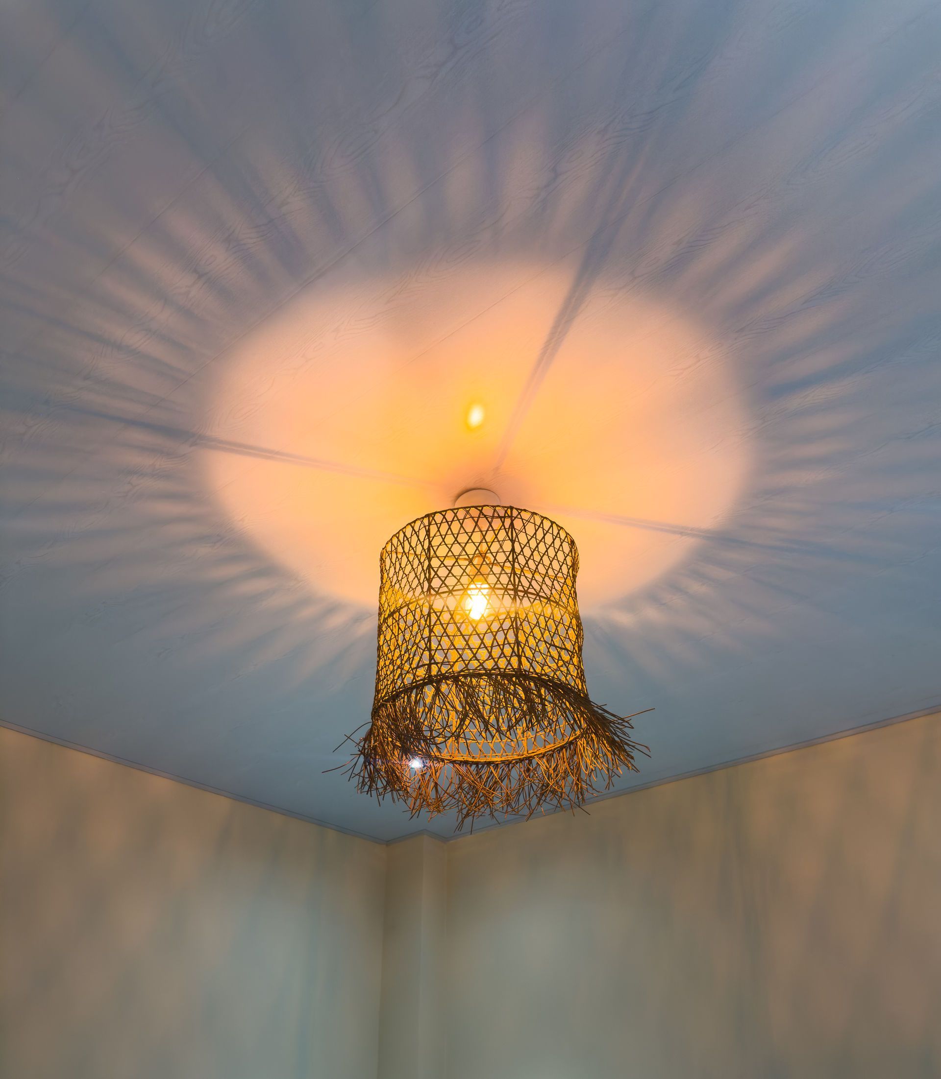 Lámpara dorada ornamentada que proyecta una luz estampada sobre un techo blanco.