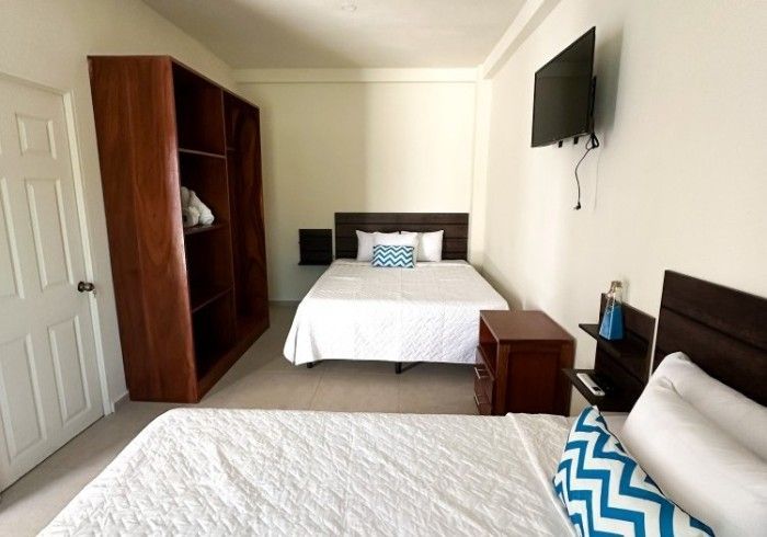 Una habitación de hotel con dos camas, un armario y un televisor.