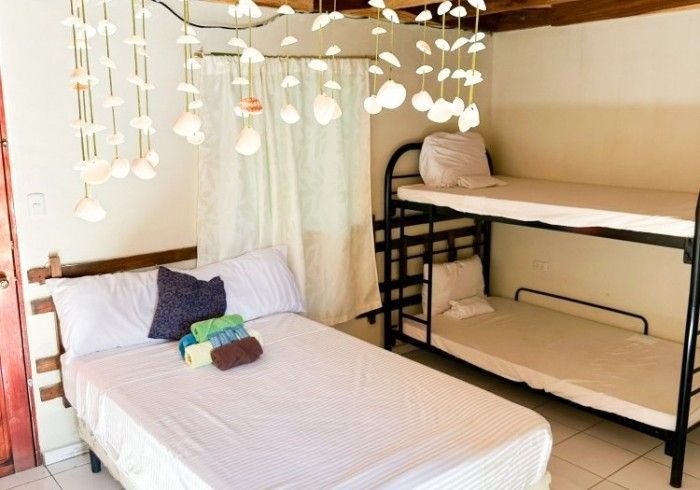 Dormitorio con cama de matrimonio y literas; luces de cadena cuelgan del techo.