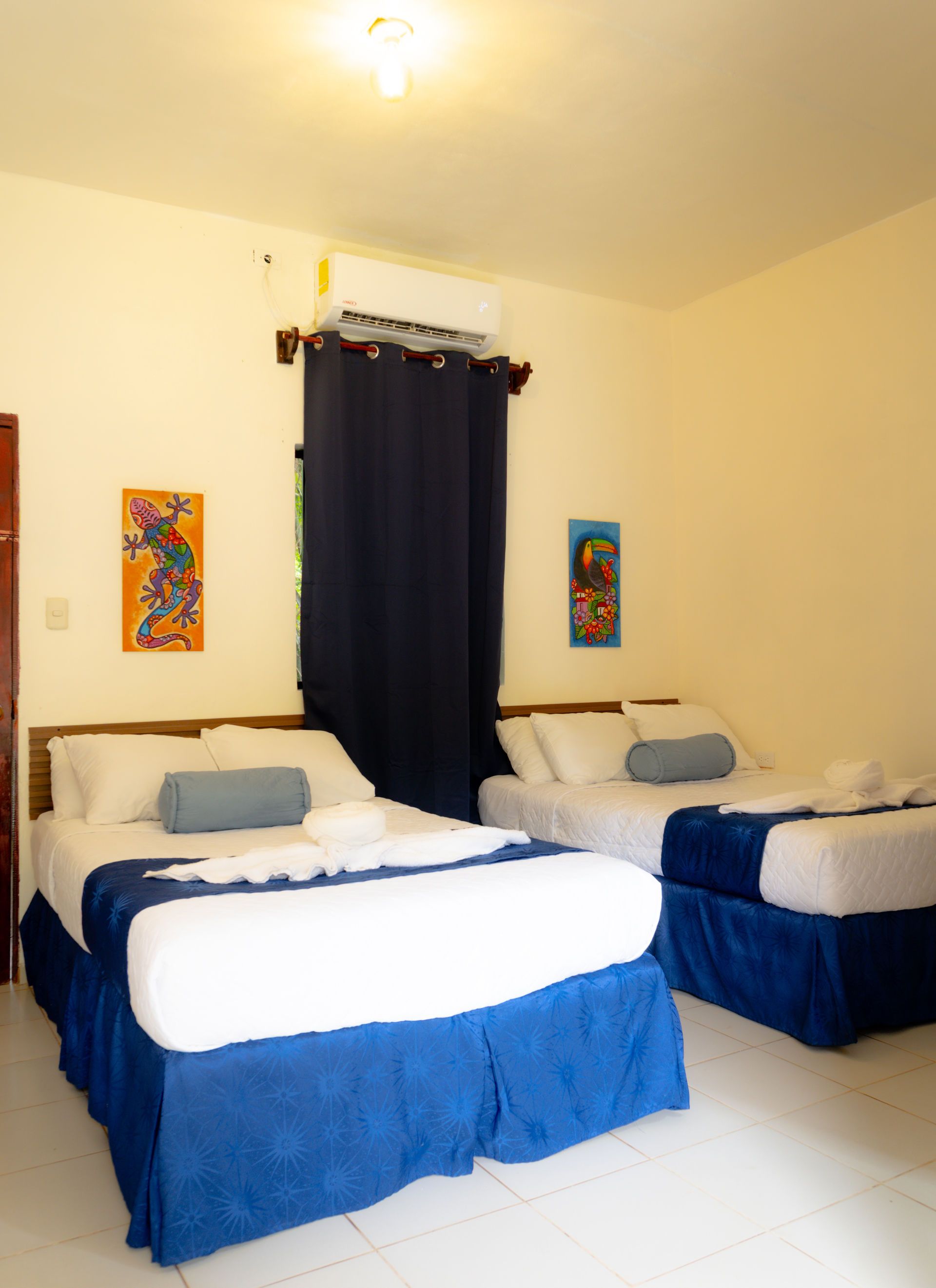 Dormitorio con cama de matrimonio y literas, iluminado por lámparas colgantes.