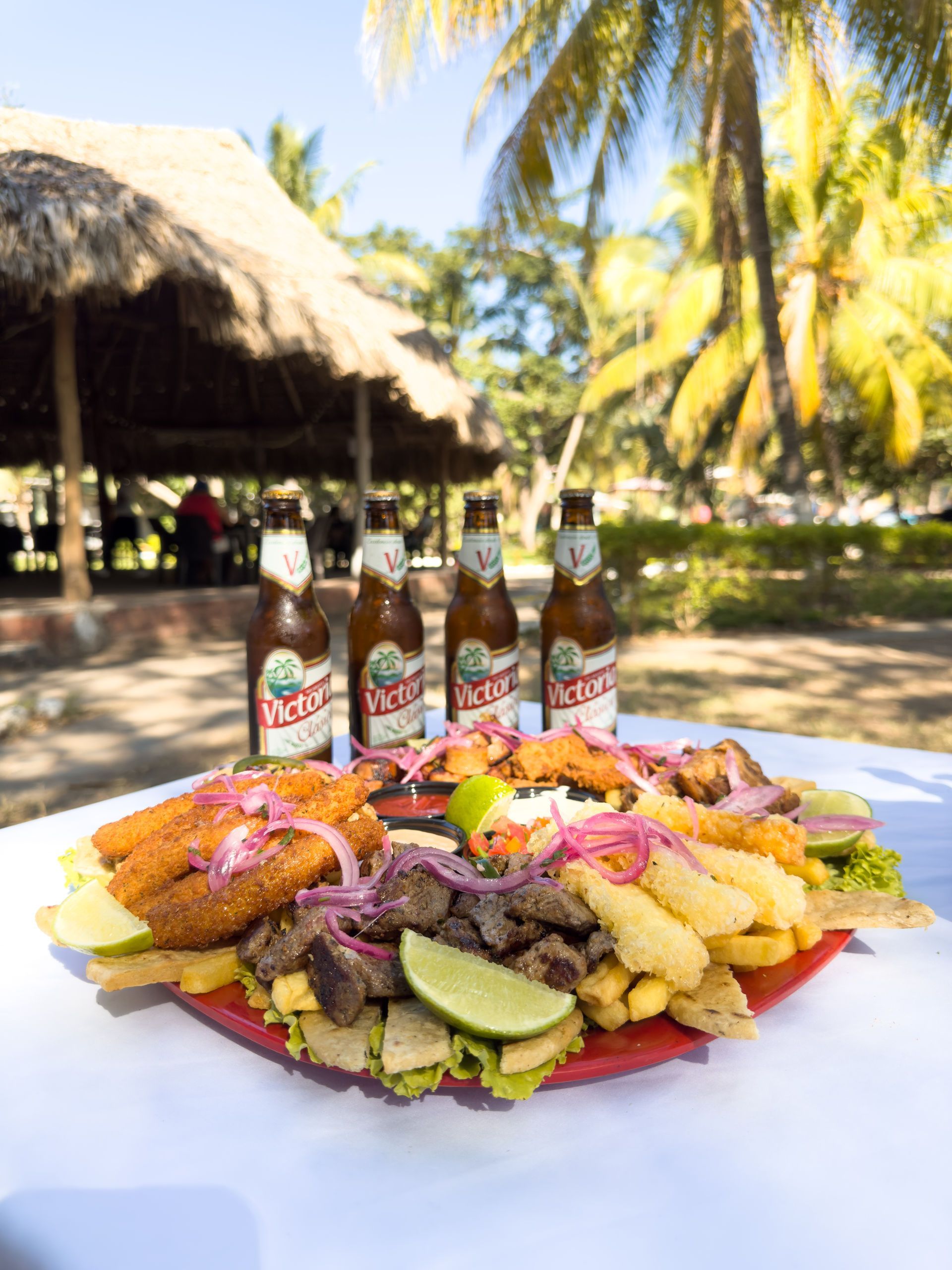 Plato de comida frita con botellas de cerveza en un restaurante al aire libre.