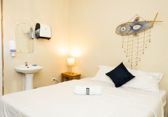 Dormitorio con cama, lavabo, espejo y decoración de pared, iluminado por una lámpara.