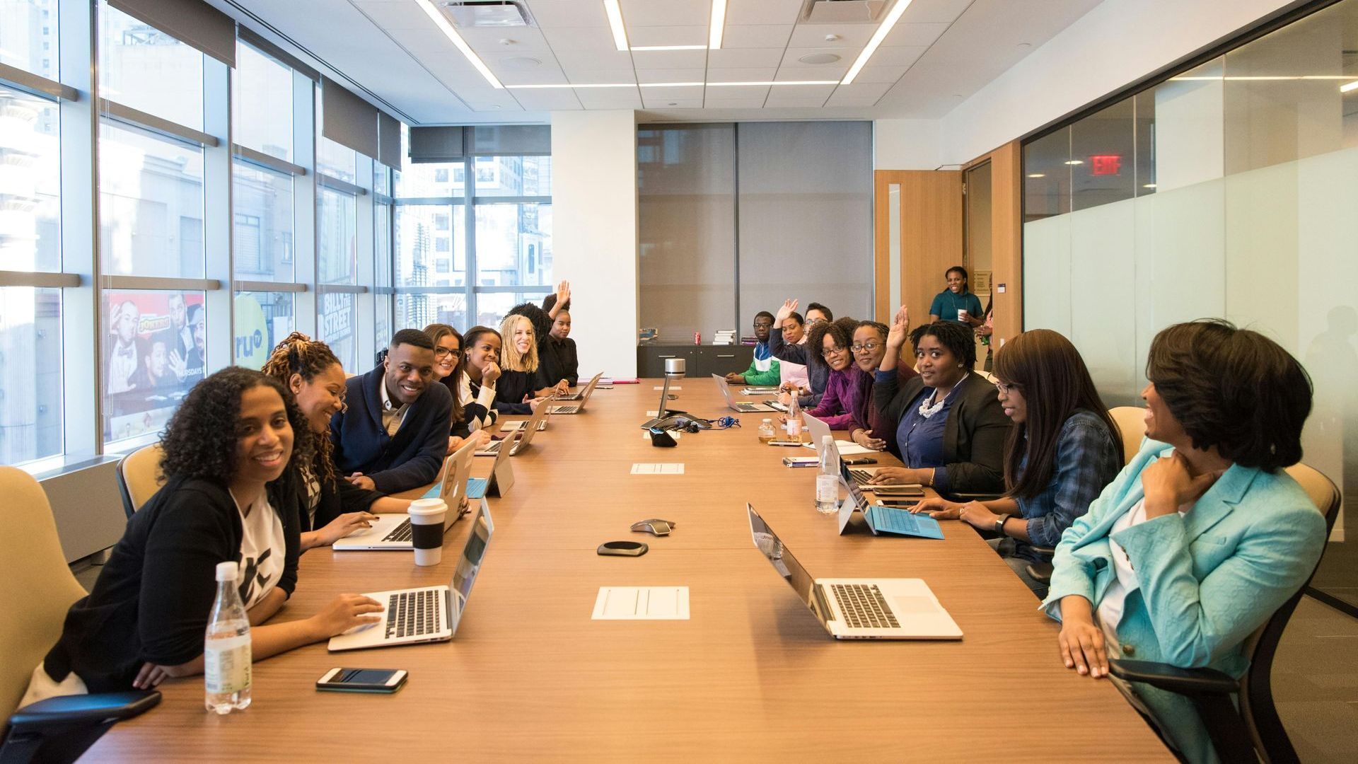 A group of people are sitting at a long table in a conference room.