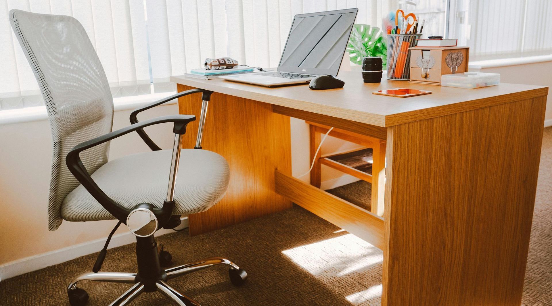 A wooden desk with a chair and a laptop on it.