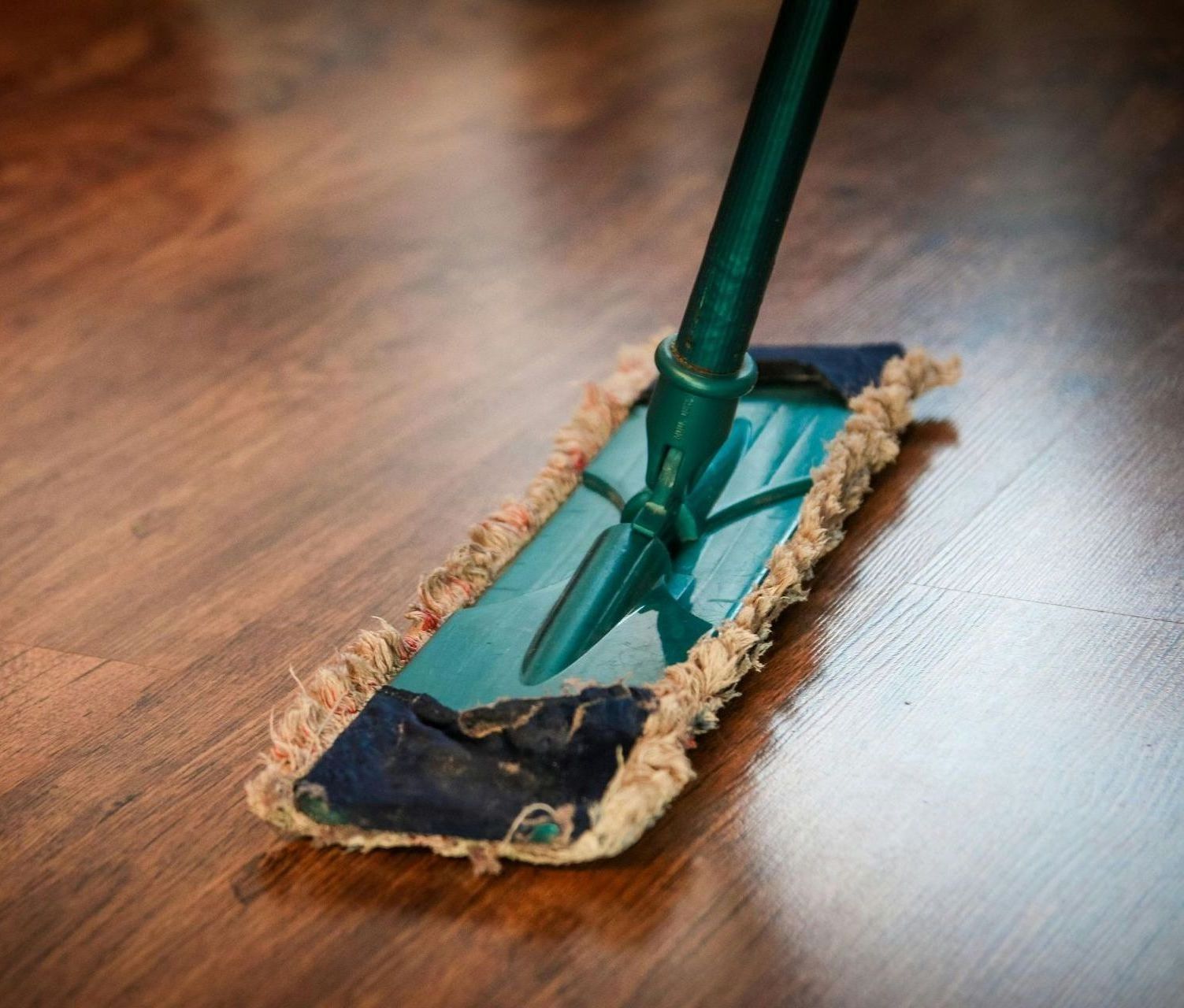A mop is being used to clean a wooden floor.