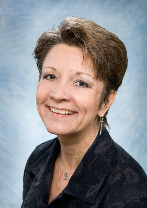 A woman wearing a black shirt and earrings smiles for the camera