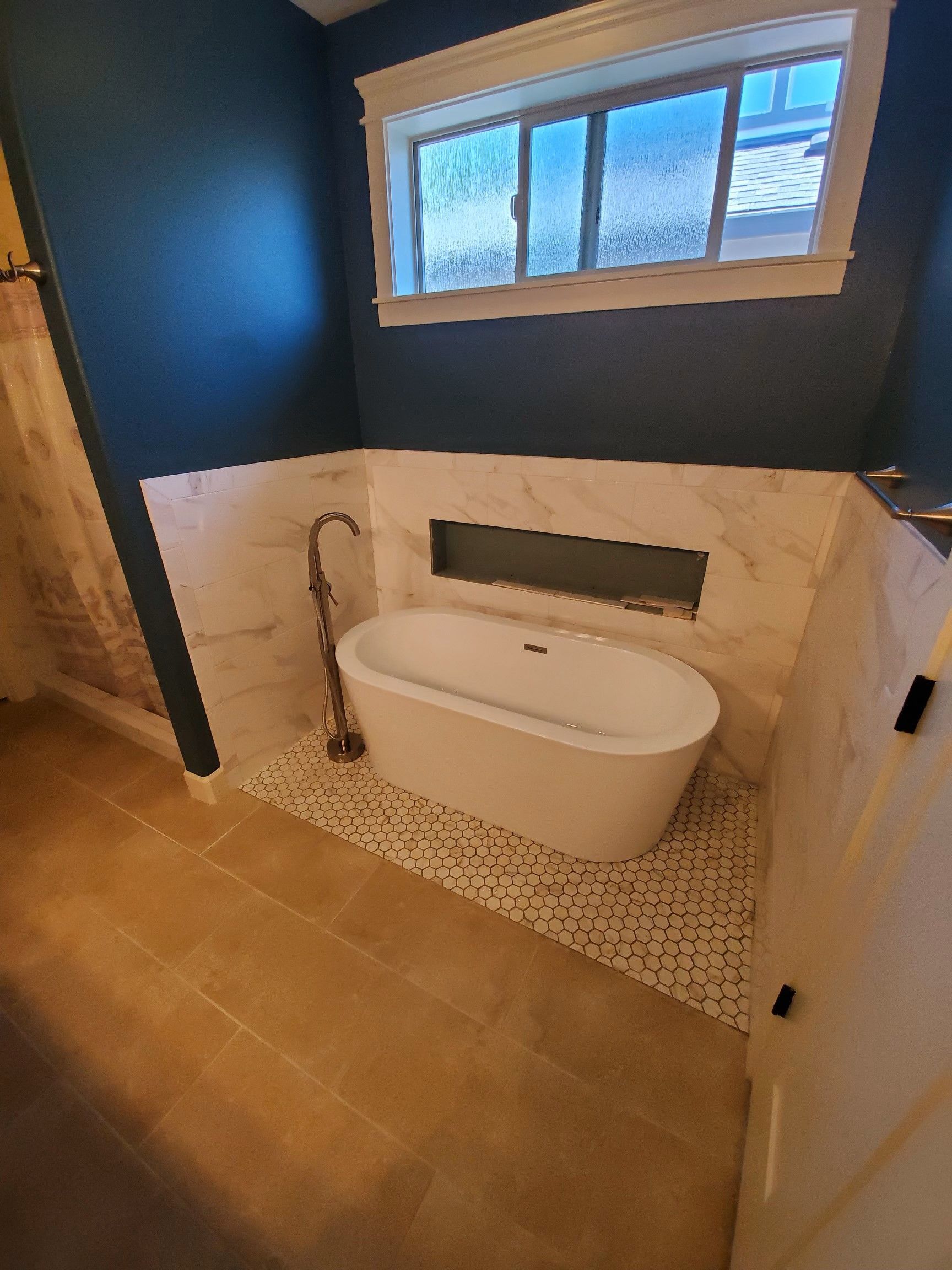 Beautiful renovated bathtub area with a modern tub, tile, and paint job.