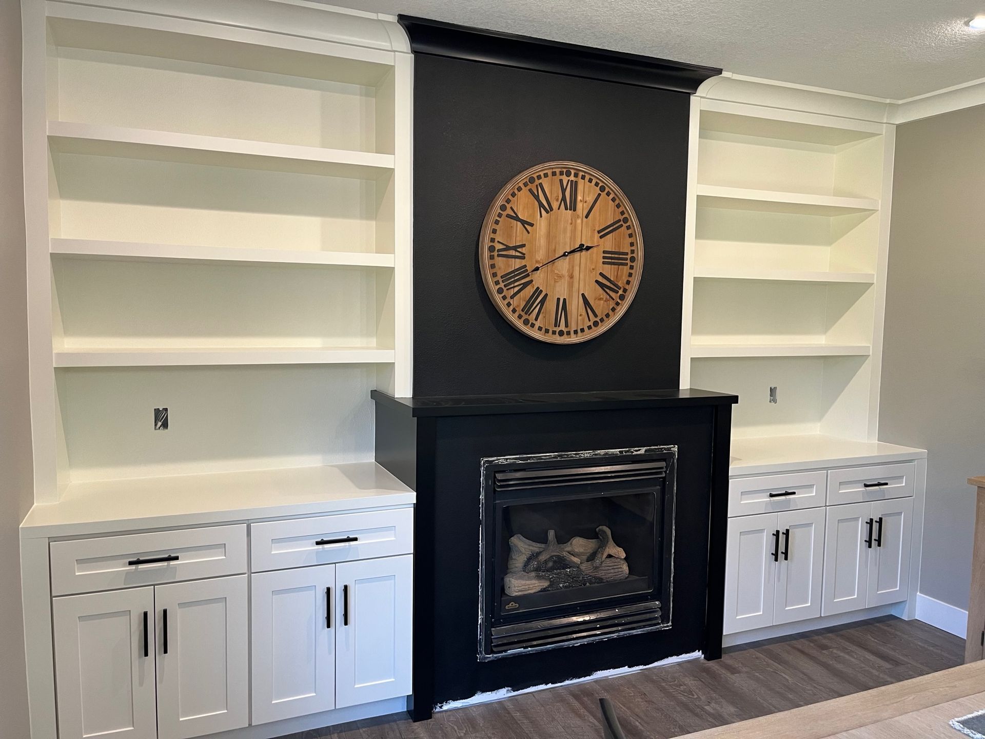 Beautiful freshly painted shelves with white cabinets and black fireplace in the between