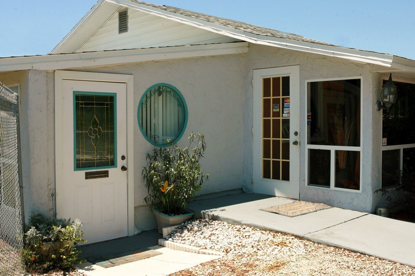 White building entrance with a ramp, two doors, and a round window.