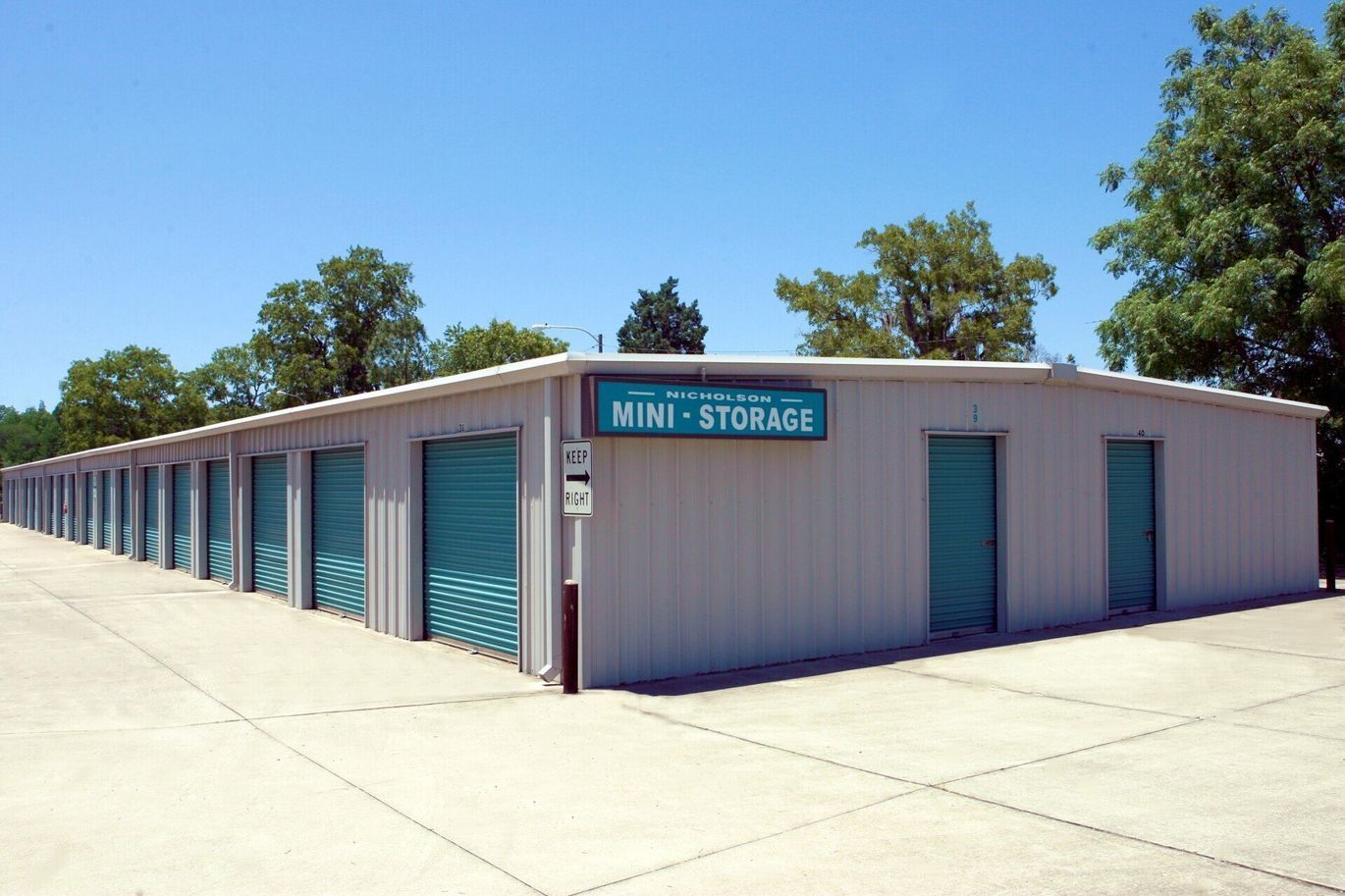 Storage facility with rows of teal doors and a sign that reads 