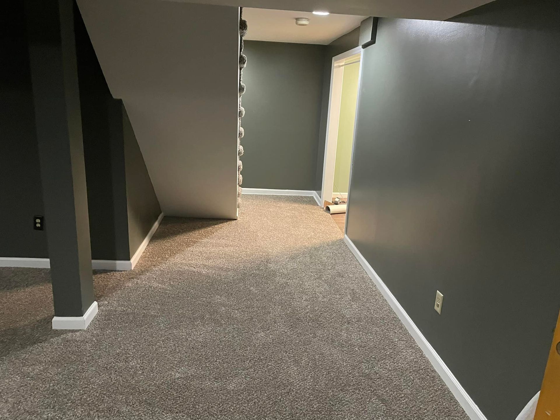 An empty basement with a carpeted floor and gray walls.