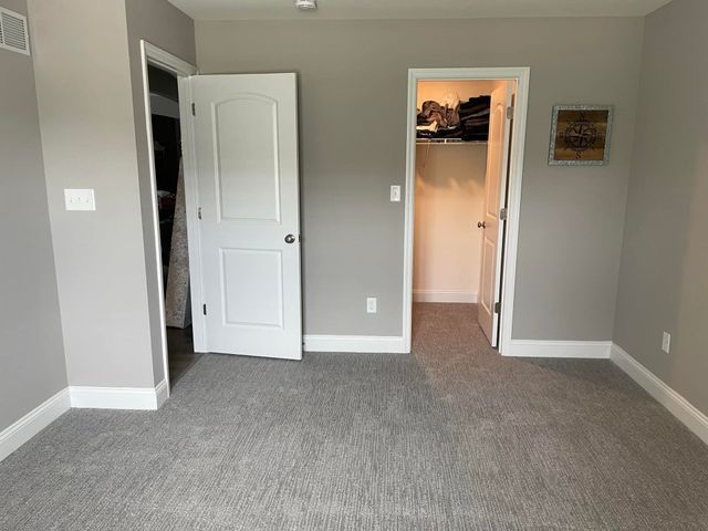 A bedroom with a carpeted floor and a closet