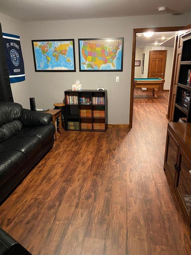 A living room with a couch , bookshelf , and pool table.