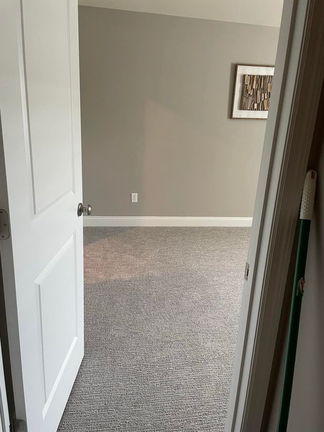 A room with a carpeted floor and a picture on the wall.