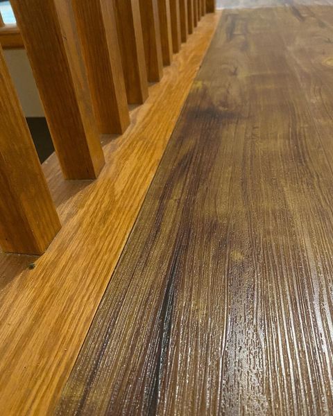 A close up of a wooden floor next to a wooden railing.