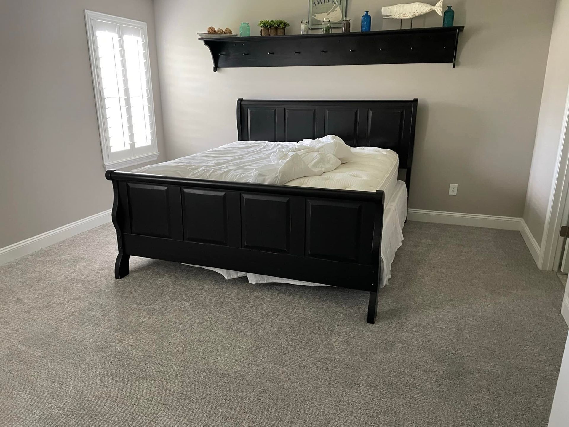 A bedroom with a bed and a shelf above it.