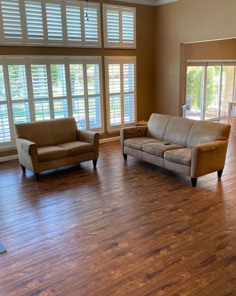 A living room with two couches and shutters on the windows.