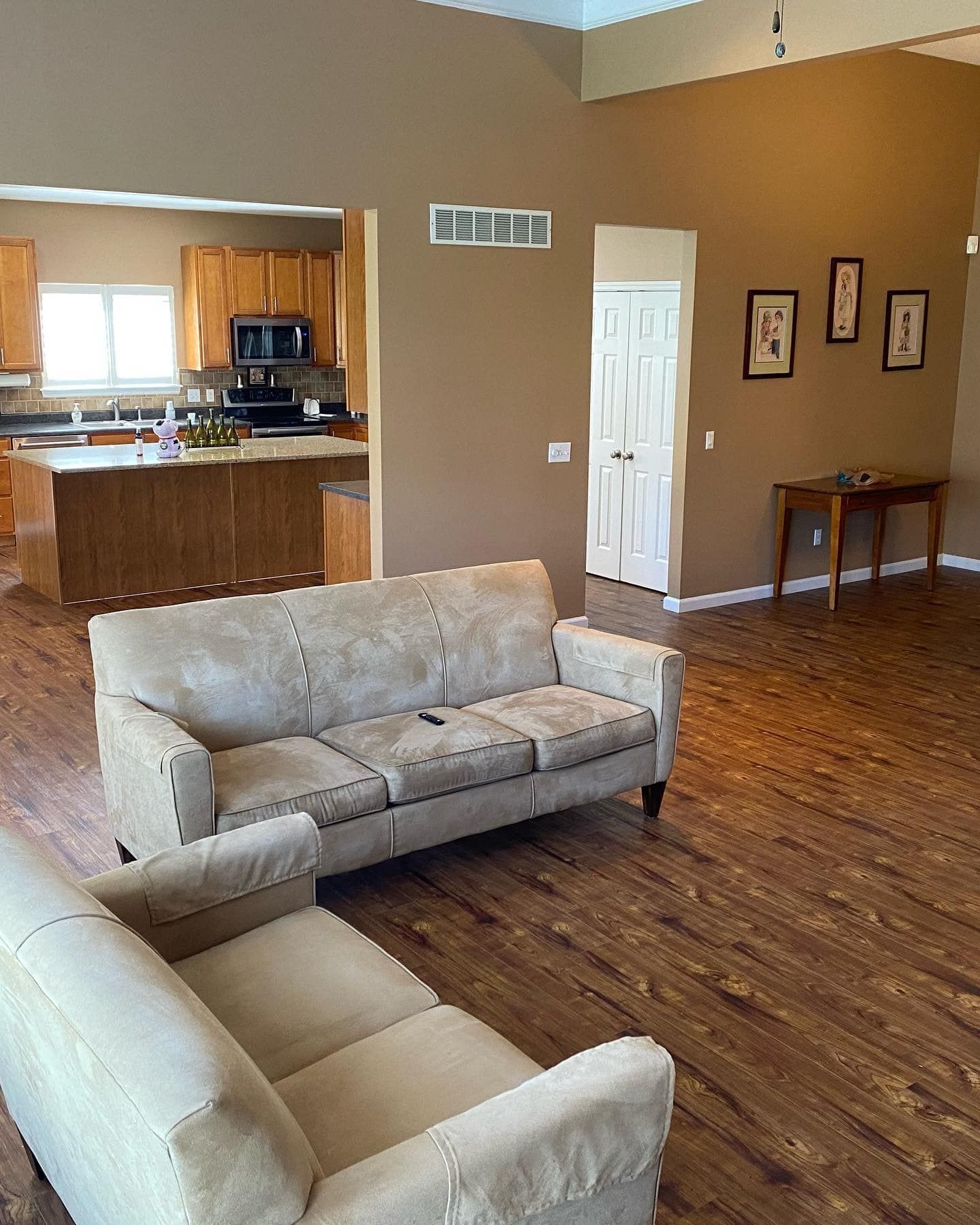 A living room with a couch and chairs and a kitchen in the background