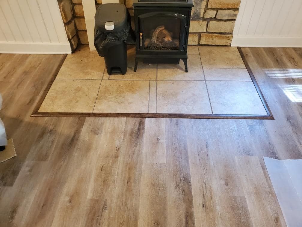 A wood stove is sitting on a tiled floor next to a fireplace.