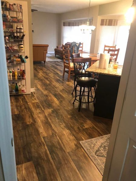 A kitchen with hardwood floors and a dining room in the background
