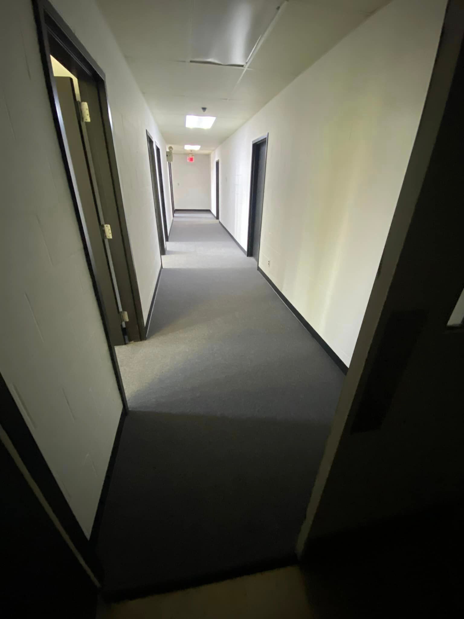 A long hallway with a gray carpet and white walls
