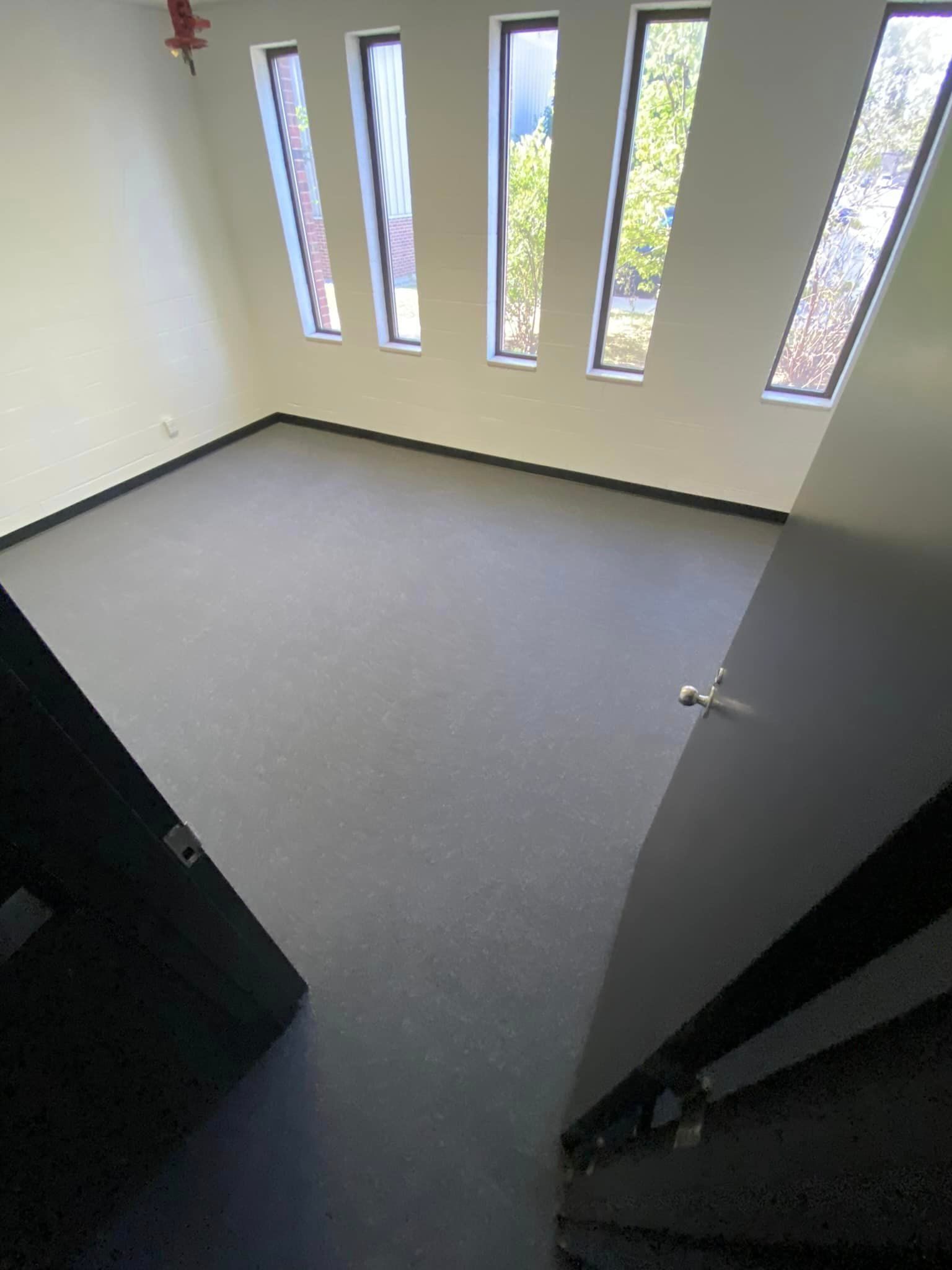 A room with a carpeted floor , stairs , and windows.