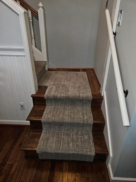 A staircase with a carpet on the steps and a wooden railing.