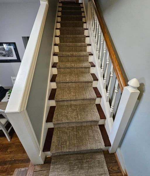 A staircase with a carpet on the steps and a wooden railing.