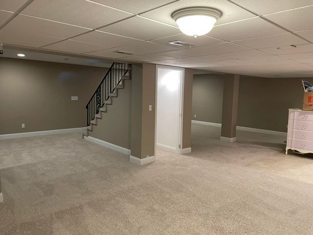An empty basement with stairs and a light on the ceiling.