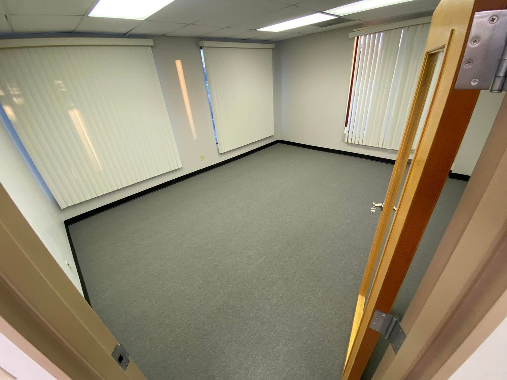 An empty room with blinds on the windows and a door