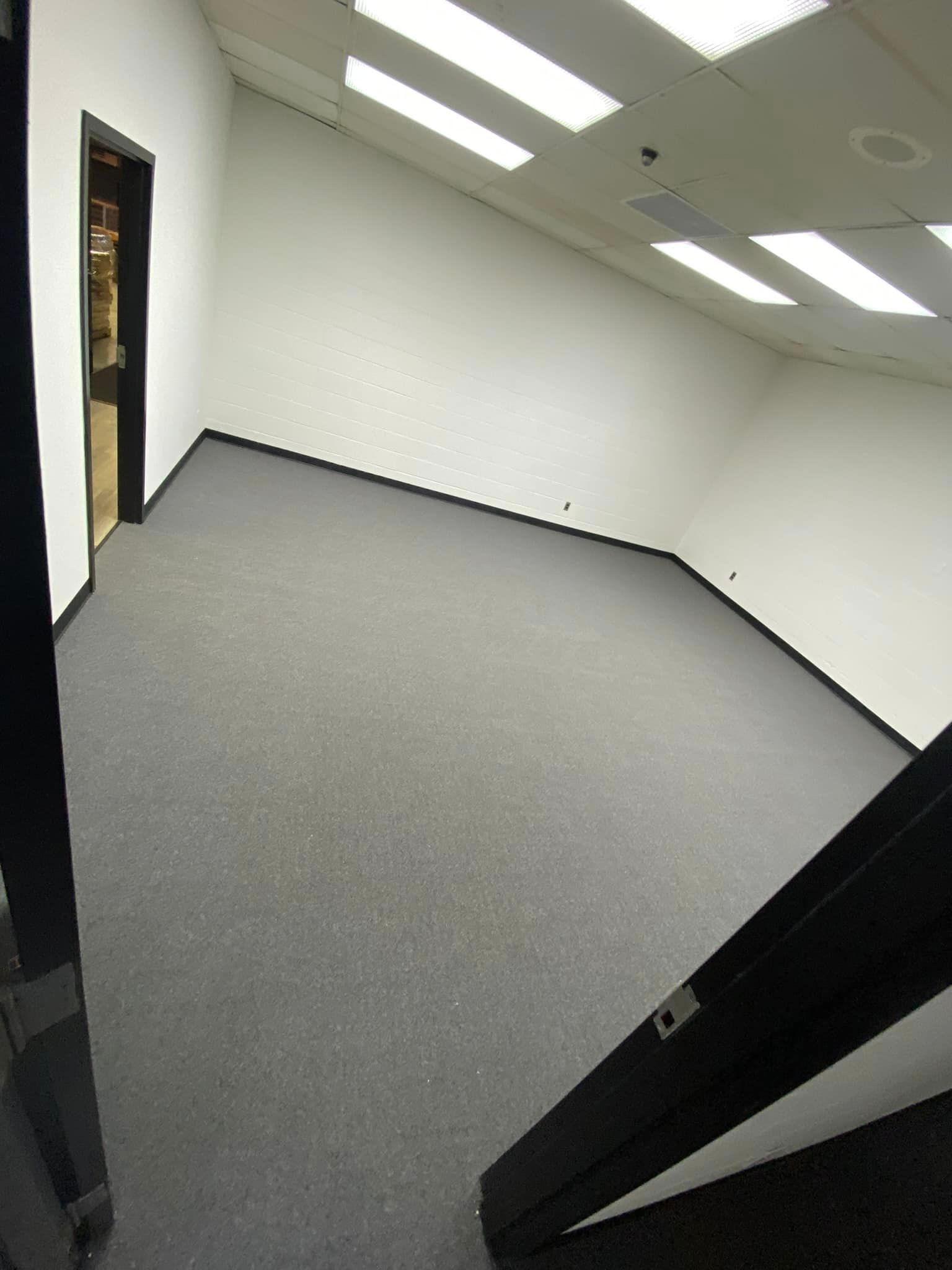 An empty room with a carpeted floor and white walls