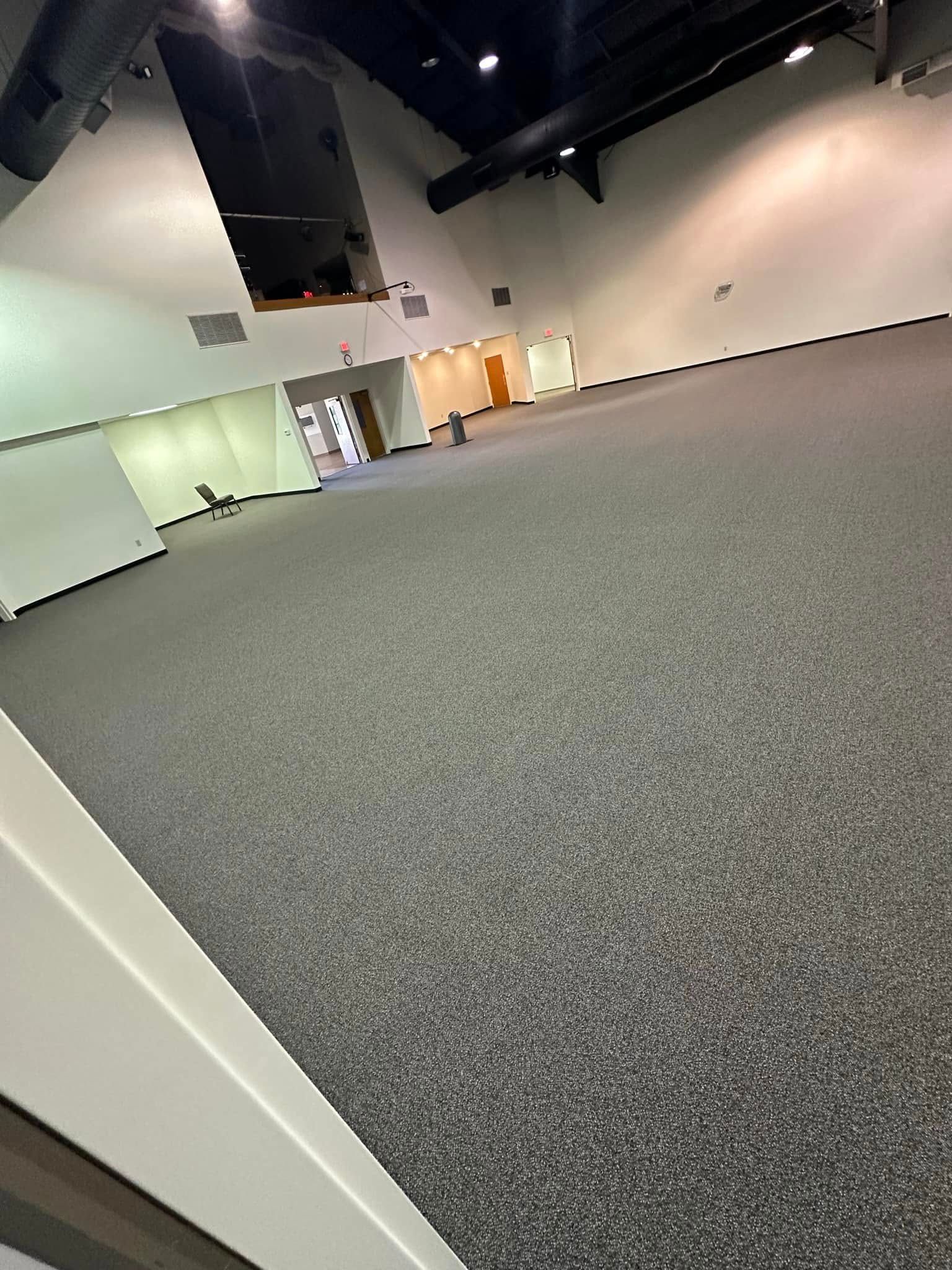 A large empty room with a carpeted floor and white walls.