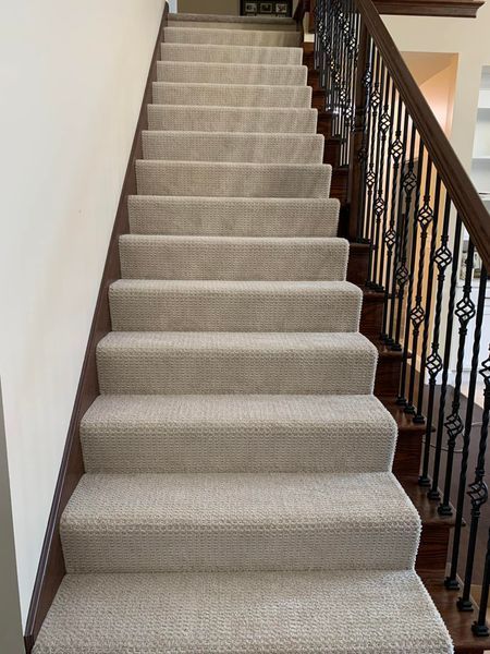 A staircase with a carpeted staircase and a wrought iron railing