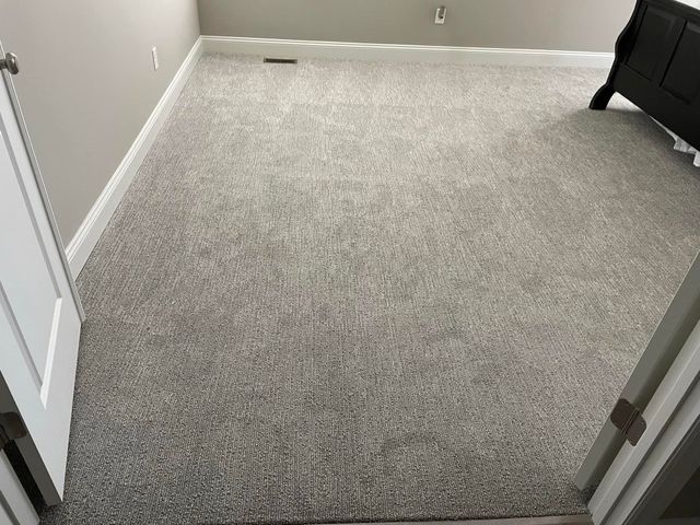 A bedroom with a carpeted floor and a bed in the corner.