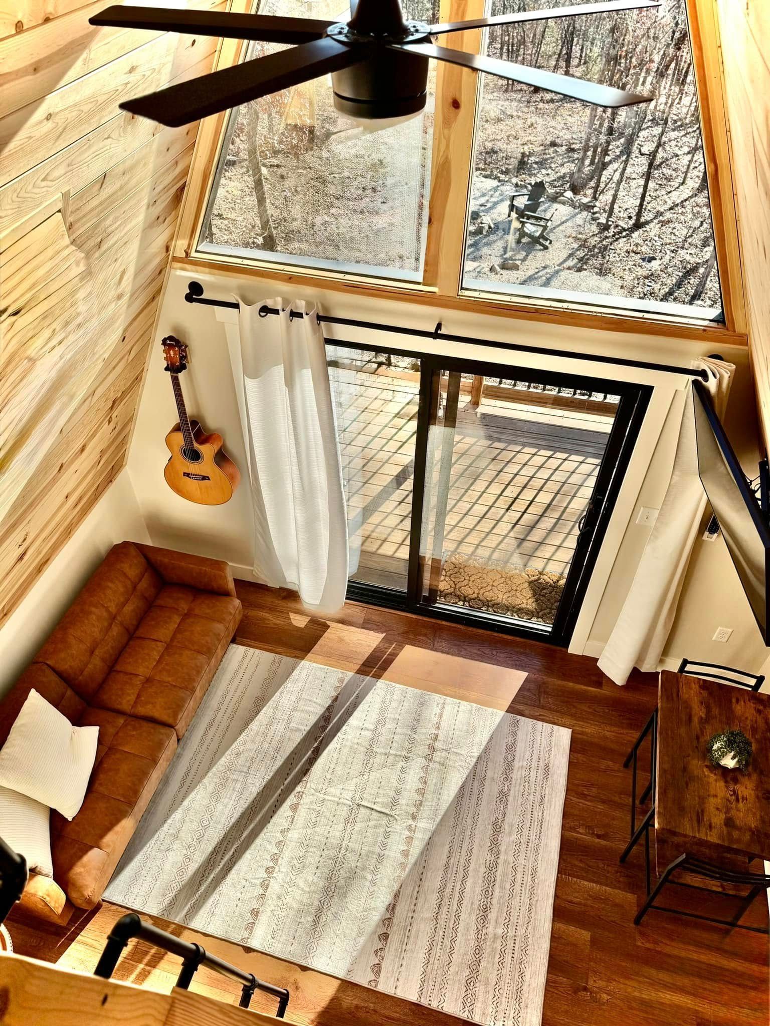 An aerial view of a living room with a couch and a guitar on the wall.