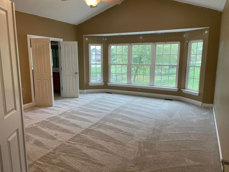 A large empty room with a lot of windows and a ceiling fan.