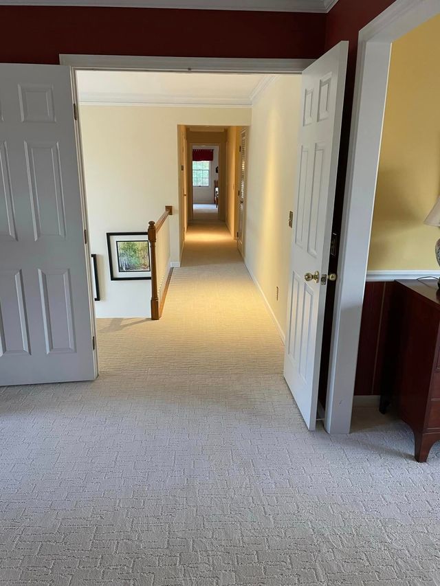 A hallway leading to a bedroom and stairs in a house.