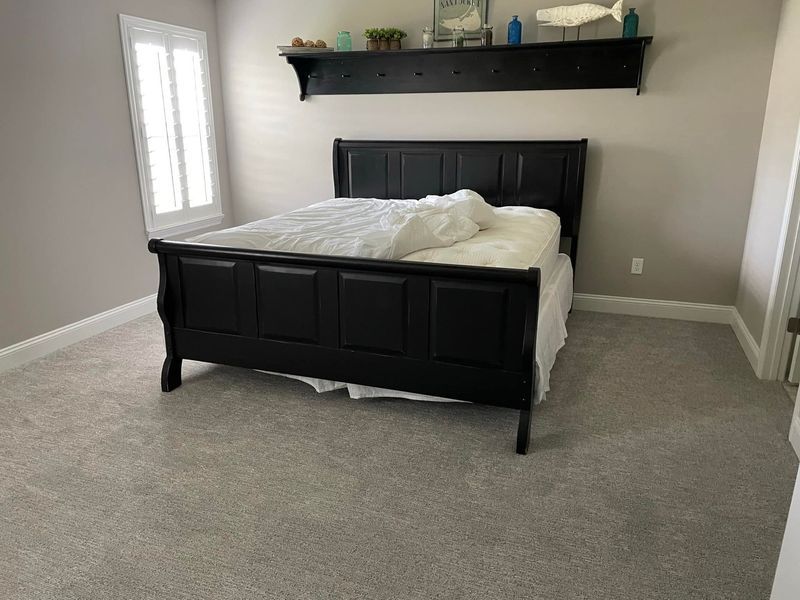 A bedroom with a bed and a shelf above it.