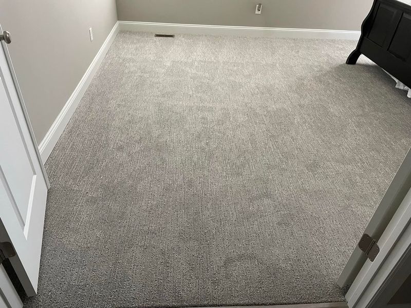 A bedroom with a bed and a carpeted floor.